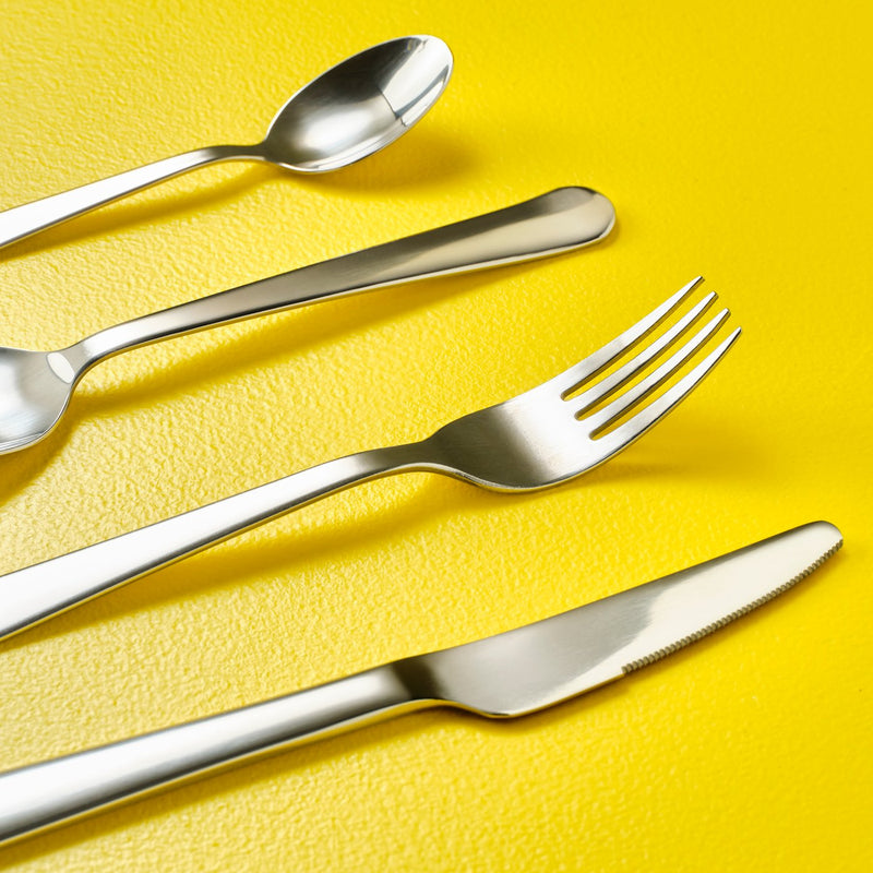 Alcune posate inox su fondo giallo
