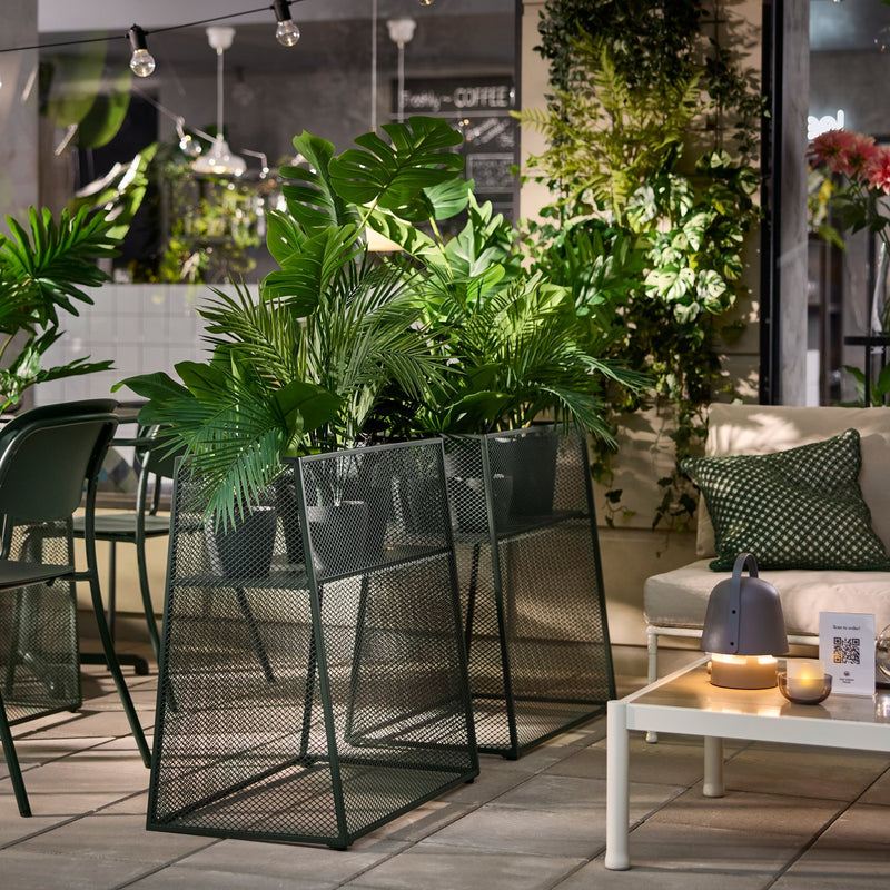 Deep green VISINGSÖ plant stands with green plants in a modern café setting with outdoor seating.